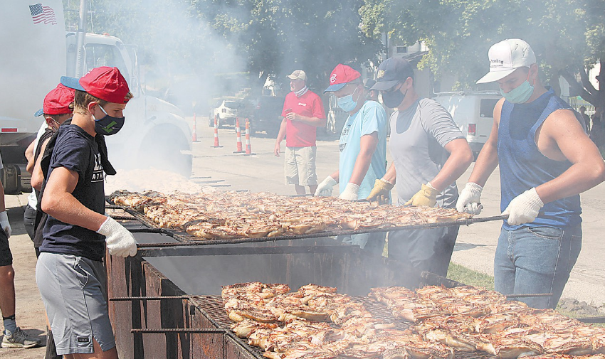 Four people preparing mass amounts of grilled chicken